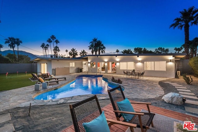 pool at dusk featuring a patio area