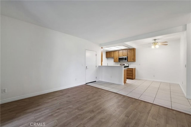 kitchen with light hardwood / wood-style floors, kitchen peninsula, ceiling fan, and appliances with stainless steel finishes