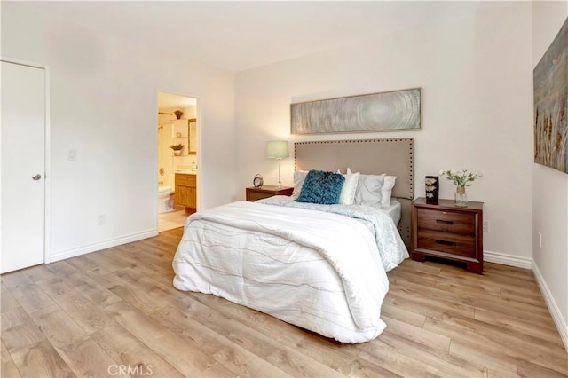 bedroom with connected bathroom and light hardwood / wood-style flooring