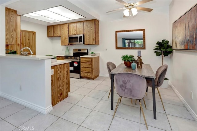 kitchen with a breakfast bar, light tile patterned floors, ceiling fan, kitchen peninsula, and stainless steel appliances