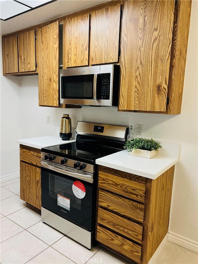 20702 El Toro Rd Unit 359, Lake Forest, CA 92630 - kitchen featuring appliances with stainless steel finishes, brown cabinets, baseboards, and light tile patterned floors