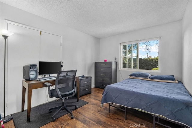 bedroom with a textured ceiling and dark hardwood / wood-style floors