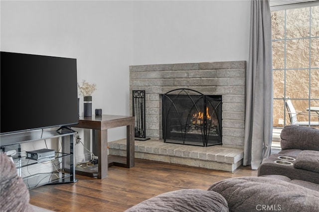 living room with a brick fireplace and hardwood / wood-style floors