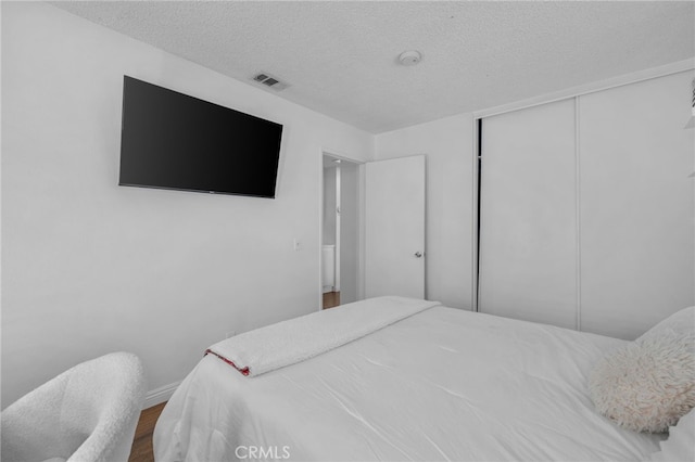 bedroom featuring a textured ceiling, a closet, and wood-type flooring