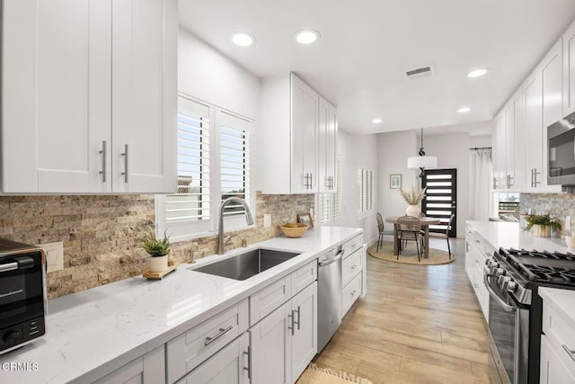 kitchen featuring light stone countertops, white cabinets, appliances with stainless steel finishes, and sink