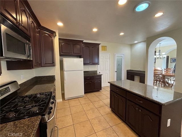 kitchen featuring a notable chandelier, light tile patterned flooring, dark stone counters, stainless steel appliances, and dark brown cabinets