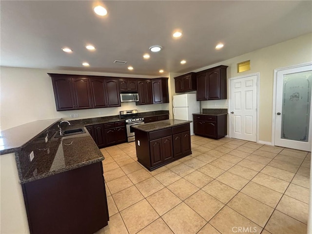 kitchen with kitchen peninsula, sink, light tile patterned flooring, stainless steel appliances, and dark brown cabinets