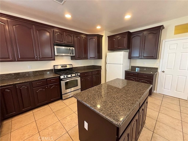 kitchen with light tile patterned floors, dark brown cabinets, stainless steel appliances, and a kitchen island