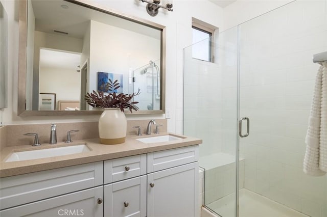 bathroom featuring a shower with shower door and vanity