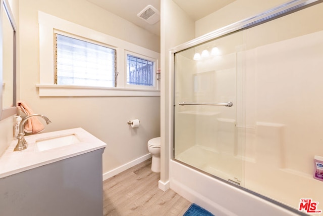 full bathroom with toilet, hardwood / wood-style floors, vanity, and shower / bath combination with glass door