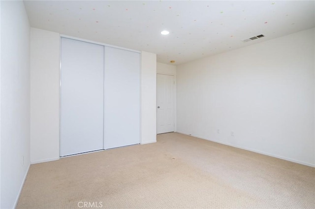 unfurnished bedroom featuring a closet and light colored carpet