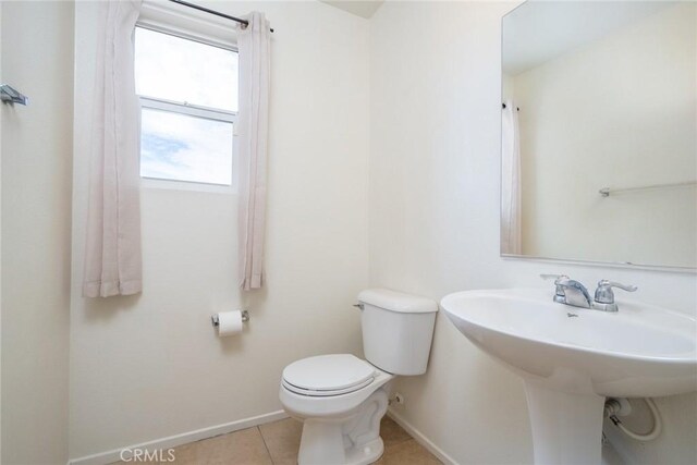 bathroom with toilet, tile patterned floors, and sink