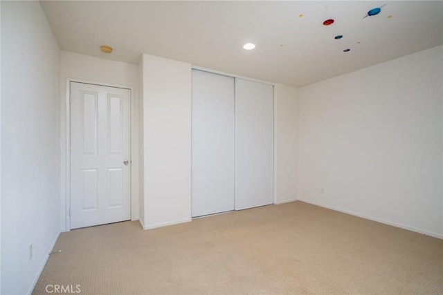 unfurnished bedroom featuring light carpet and a closet