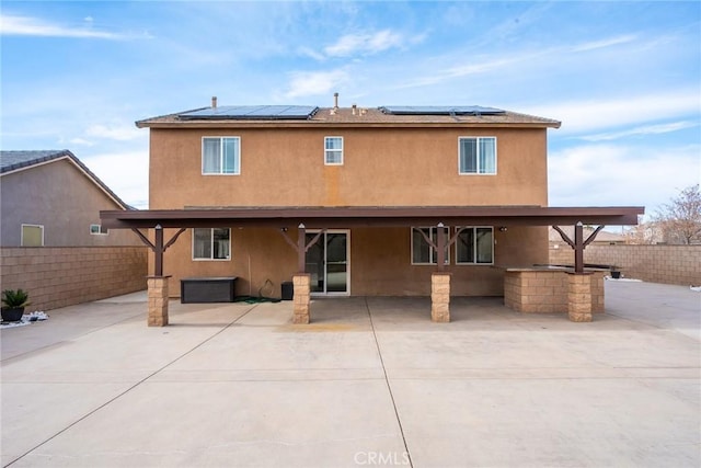 rear view of property featuring solar panels and a patio