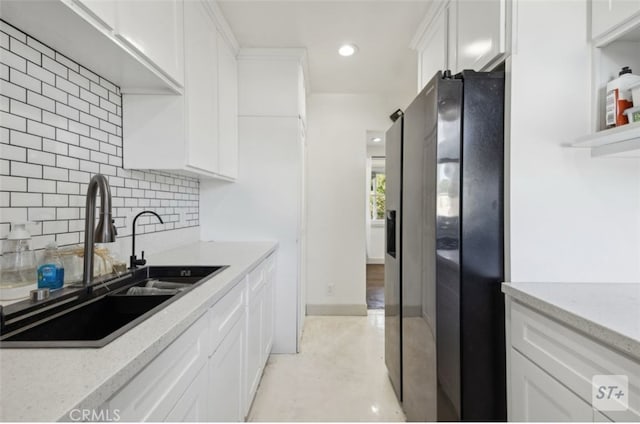 kitchen with refrigerator with ice dispenser, backsplash, white cabinets, light stone counters, and sink