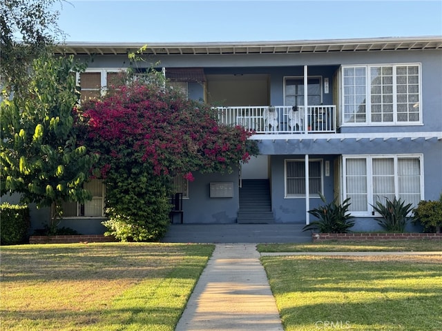 view of front of home featuring a balcony and a front yard