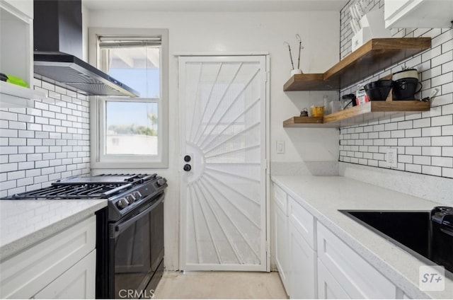 kitchen with black appliances, white cabinets, backsplash, and wall chimney range hood