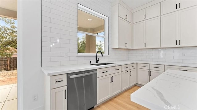 kitchen with light stone countertops, dishwasher, white cabinetry, a healthy amount of sunlight, and sink