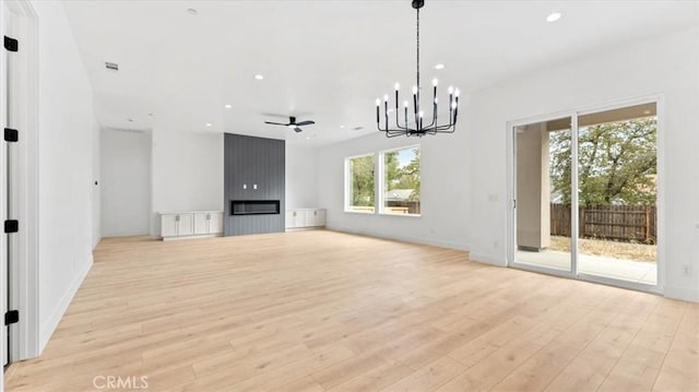 unfurnished living room featuring a fireplace, ceiling fan with notable chandelier, a wealth of natural light, and light hardwood / wood-style floors