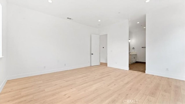 unfurnished bedroom featuring ensuite bath and light wood-type flooring