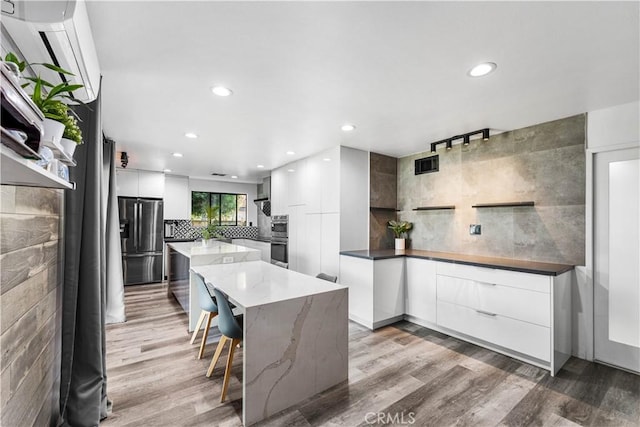 kitchen featuring tasteful backsplash, white cabinets, stainless steel appliances, and a kitchen island