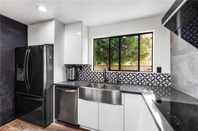 kitchen with hardwood / wood-style floors, white cabinets, sink, black fridge with ice dispenser, and stainless steel dishwasher