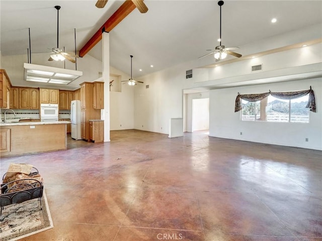 unfurnished living room with beam ceiling, sink, and high vaulted ceiling