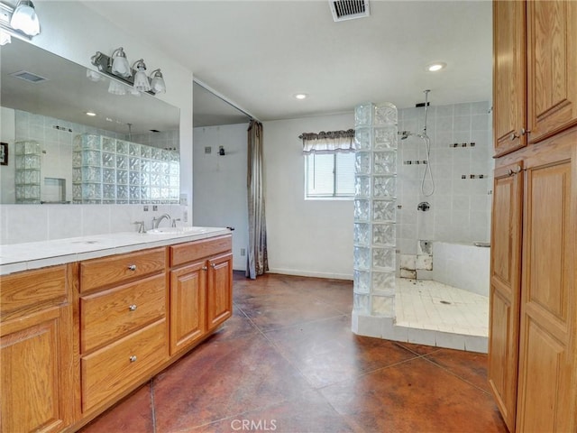 bathroom featuring tasteful backsplash, tile patterned flooring, sink, and tiled shower