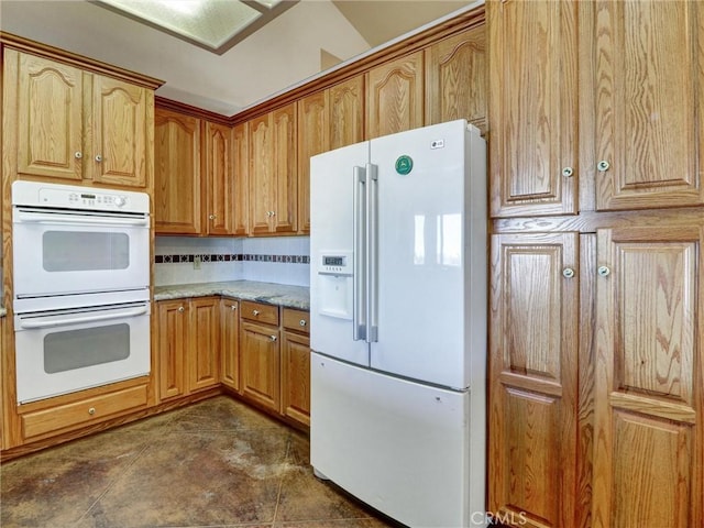 kitchen featuring decorative backsplash, light stone countertops, and white appliances