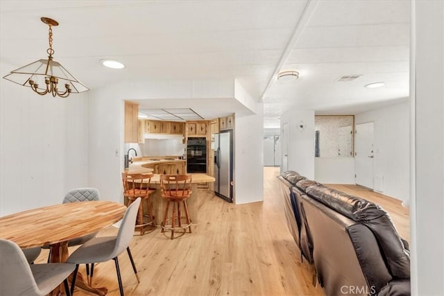 dining area featuring a chandelier, visible vents, and light wood finished floors