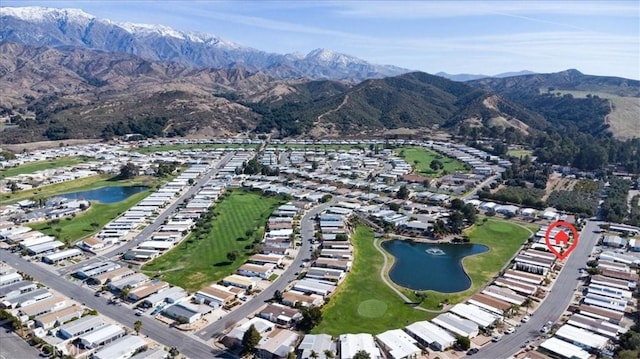 drone / aerial view with view of golf course and a water and mountain view