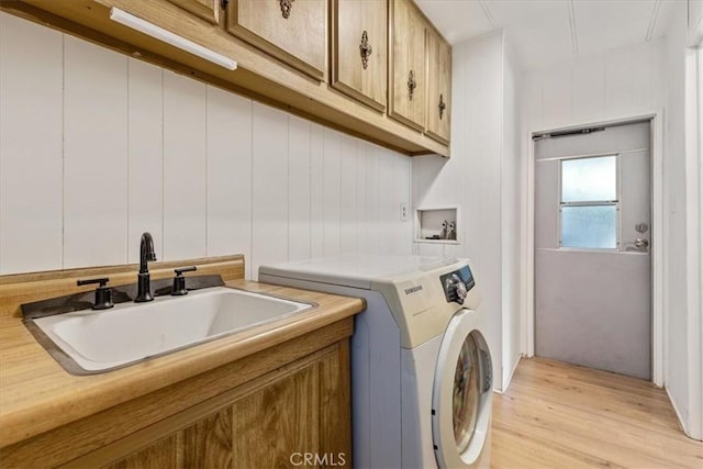 washroom featuring cabinet space, light wood finished floors, a sink, and independent washer and dryer