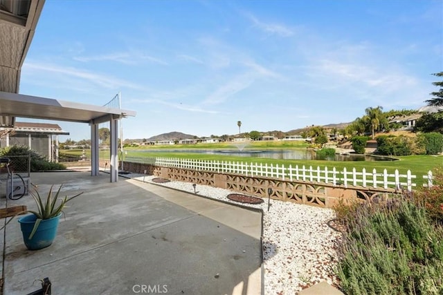 view of patio with a water view and fence