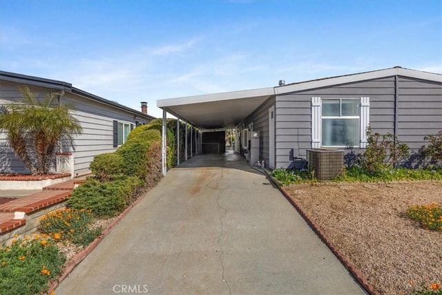 view of property exterior featuring an attached carport, concrete driveway, and central air condition unit