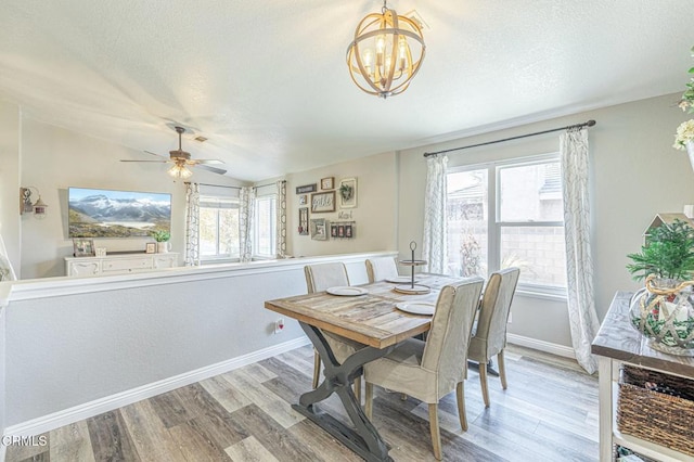 dining room featuring a textured ceiling, ceiling fan with notable chandelier, vaulted ceiling, and light hardwood / wood-style floors