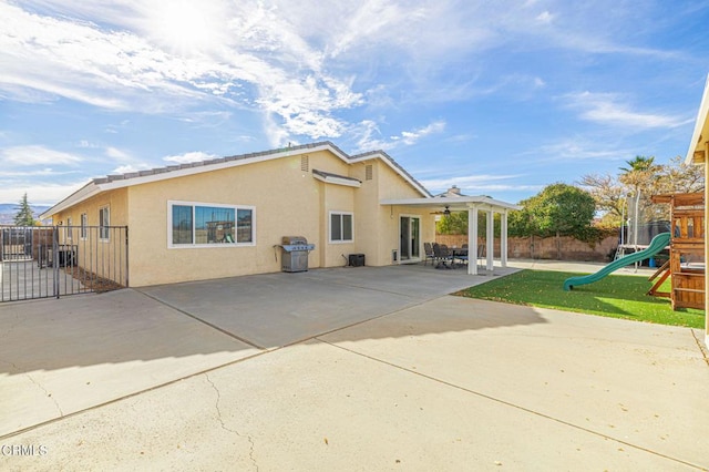 back of property featuring ceiling fan, a patio, and a playground