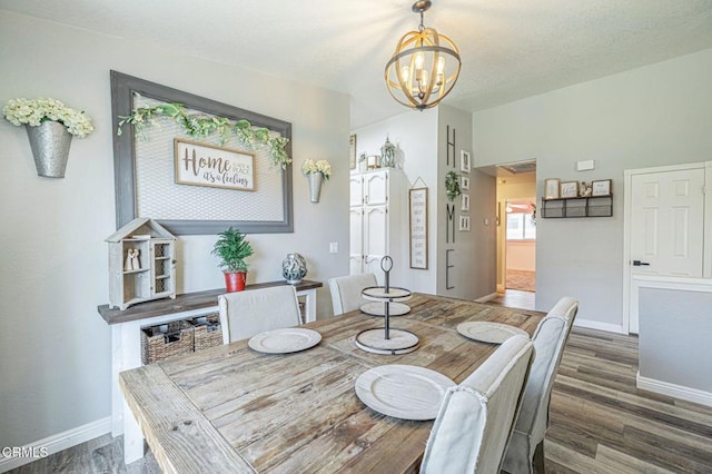 dining area featuring a chandelier, baseboards, and wood finished floors