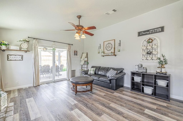 living area with visible vents, ceiling fan, baseboards, and wood finished floors