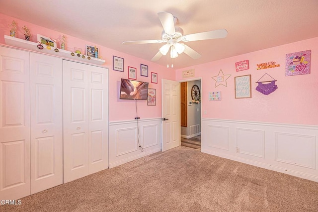 unfurnished bedroom with carpet flooring, visible vents, a closet, and wainscoting