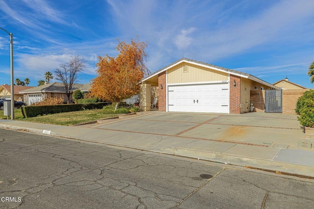 view of front of house with brick siding, an attached garage, driveway, and a gate