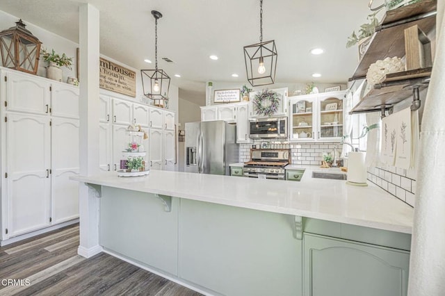 kitchen with white cabinetry, a peninsula, stainless steel appliances, and a sink