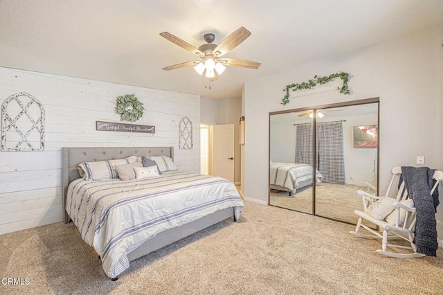 carpeted bedroom featuring a ceiling fan, a closet, and wood walls