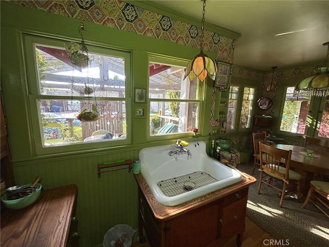 interior space with a wealth of natural light, crown molding, hanging light fixtures, and sink