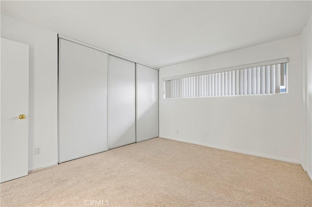 unfurnished bedroom with light carpet and a closet