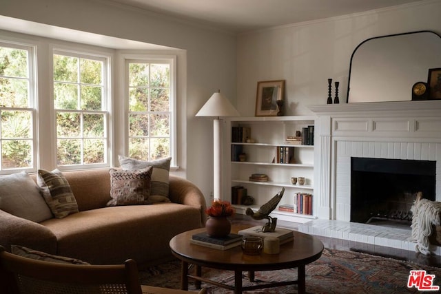 living room featuring a brick fireplace and crown molding