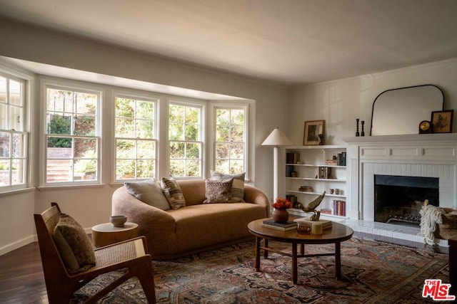 living room with a brick fireplace, dark hardwood / wood-style flooring, and plenty of natural light