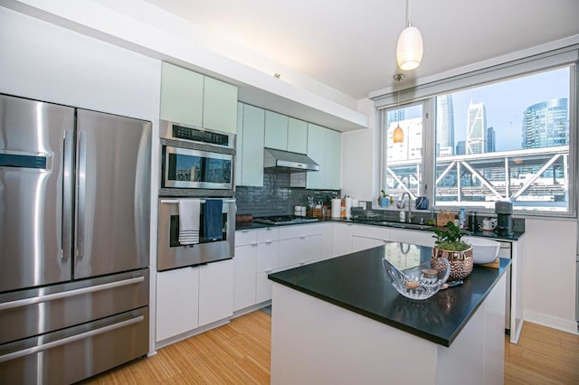 kitchen featuring ventilation hood, stainless steel appliances, sink, light hardwood / wood-style floors, and white cabinetry