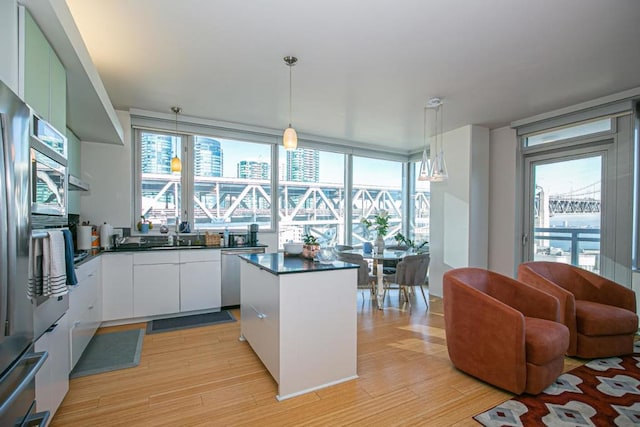 kitchen featuring stainless steel dishwasher, light hardwood / wood-style flooring, white cabinets, a center island, and hanging light fixtures