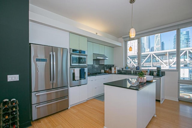 kitchen with decorative backsplash, appliances with stainless steel finishes, pendant lighting, white cabinets, and a kitchen island