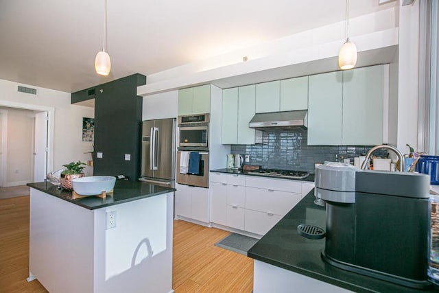 kitchen featuring white cabinetry, tasteful backsplash, a kitchen island, exhaust hood, and appliances with stainless steel finishes